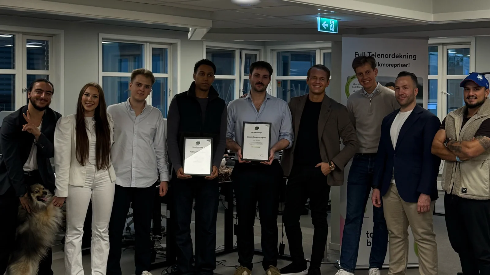 Teamet i Salgskompetanse med diplomer for månedens selger foran en Talkmore-plakat